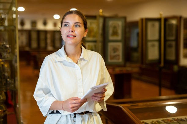 拿着小册子参观博物馆的年轻女子图片下载