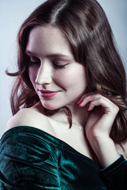 快乐微笑的美女闭着眼睛，手靠近她的脸，温柔地看着。图片下载