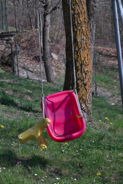 在一个废弃的操场上，坏掉的紫黄色秋千图片下载