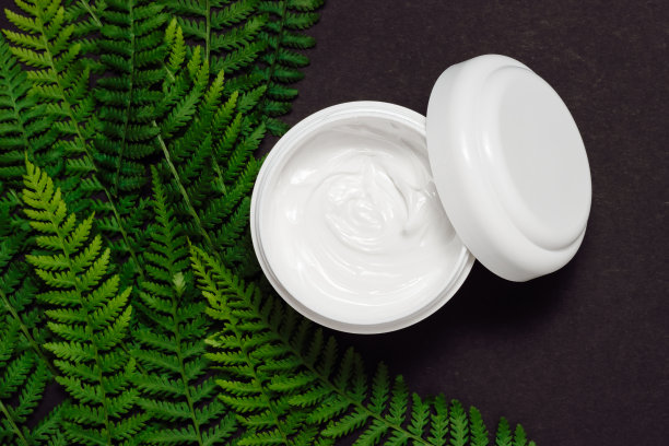 打开化妆品面霜罐与蕨类叶子在黑色背景顶部视图图片下载