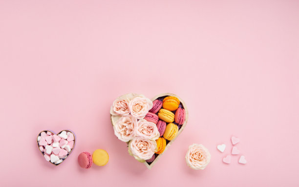 饼干马卡龙在礼盒，玫瑰花和糖果在粉红色的背景。节日礼品概念图片下载