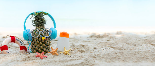 夏天在派对上。潮人菠萝时尚，戴着太阳镜，涂着防晒霜，穿着凉鞋，在沙滩上听音乐图片下载