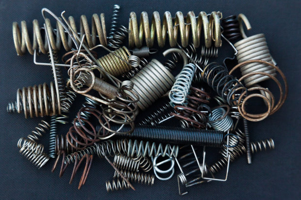 许多大小不一的小弹簧在黑色的背景下堆成一堆。图片下载