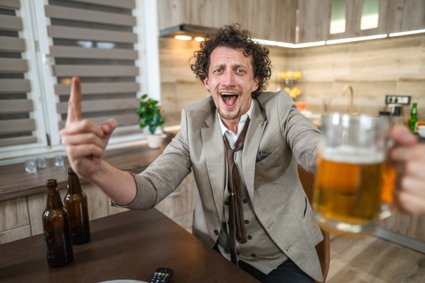 兴奋的白人一边看着电视上的足球比赛一边欢呼，喝着啤酒图片下载
