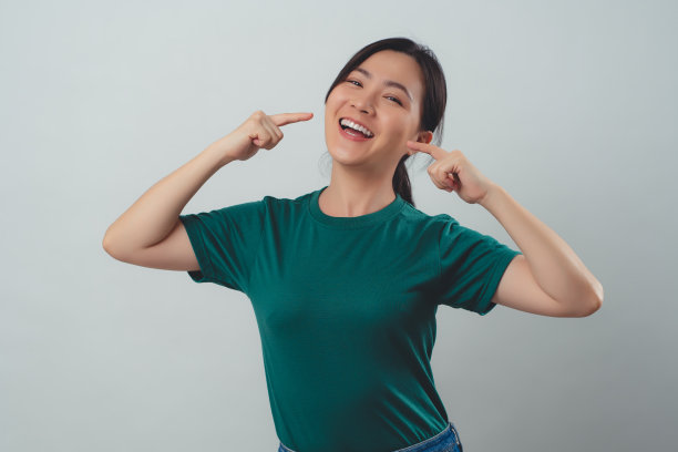 亚洲女人开心地露出露齿的微笑，孤立地站在白色的背景上。图片下载