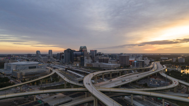 广阔的鸟瞰图，巨大的交通枢纽与高速公路，以及多个立交桥，在清晨日出的背景下，奥兰多市中心的远景。图片下载