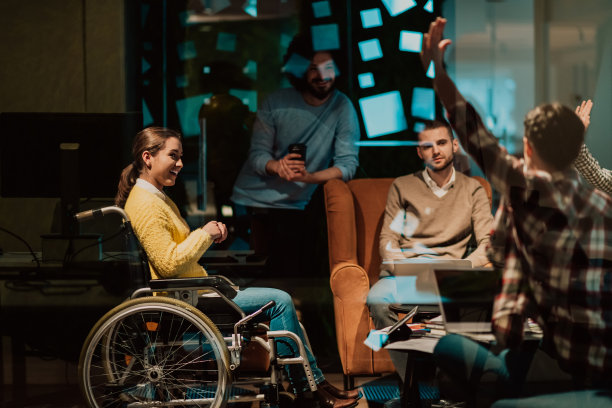 坐在轮椅上的女商人在现代化的办公室里与团队开会。一群年轻的自由职业者就新的在线商业项目达成一致图片下载