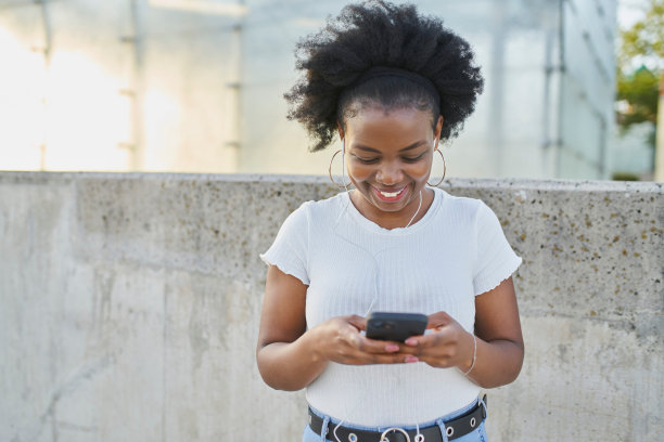 微笑的年轻女子拿着手机在城市里发短信图片下载