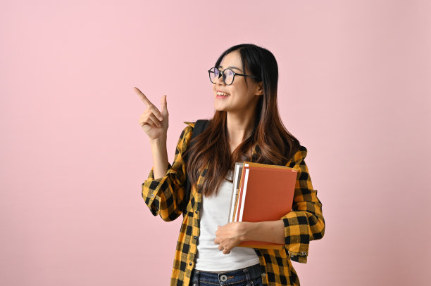 漂亮的亚洲女大学生用她的课本指着空白的地方图片下载