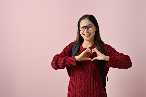 微笑的年轻亚洲女大学生展示心形，爱的手势图片下载