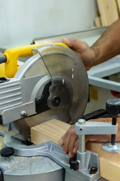 一位经验丰富的木匠正在木工车间使用电动圆锯工作。图片下载
