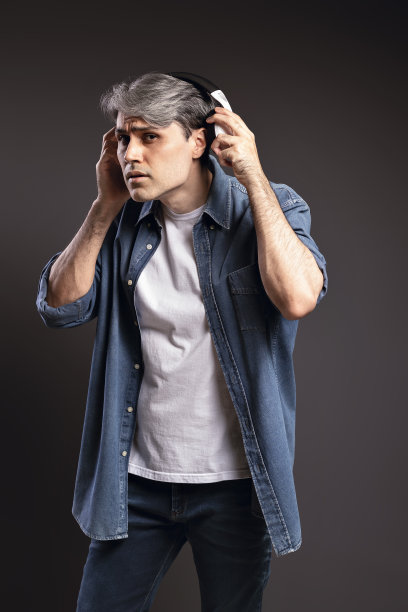 一个巴西男人的肖像，穿着衬衫和牛仔裤，拿出耳机听谈话，灰色头发-彩色照片-巴西图片下载