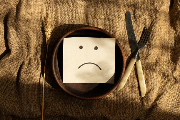 一个悲伤的微笑是画在一张卡片上的，躺在桌子上的一个粘土盘子里，没有东西吃和悲伤，心情不好图片下载