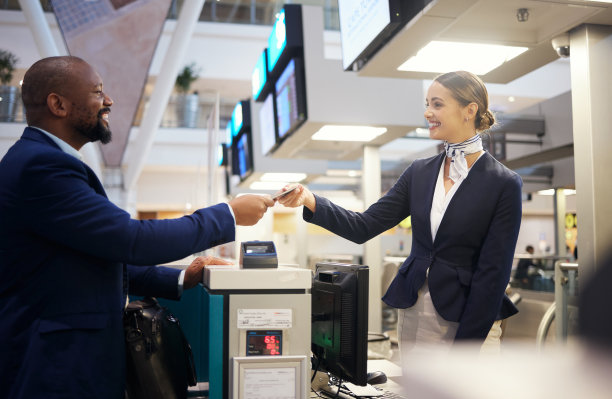 机票，机场和客户服务人员，前台支持和护照登记帮助。美国黑人男子和旅行社代理人，负责机票预订，为客户的善意和感谢而递纸和微笑图片下载