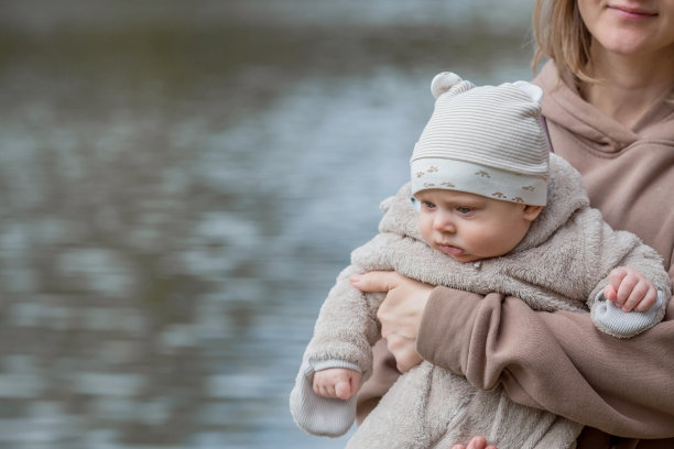 一位年轻的母亲怀里抱着一个可爱的小儿子。孩子看着镜头笑了。这是一个4个月大的小宝宝的照片。图片下载