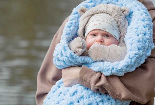 一位年轻的母亲怀里抱着一个可爱的小儿子。孩子看着镜头笑了。这是一个4个月大的小宝宝的照片。图片下载