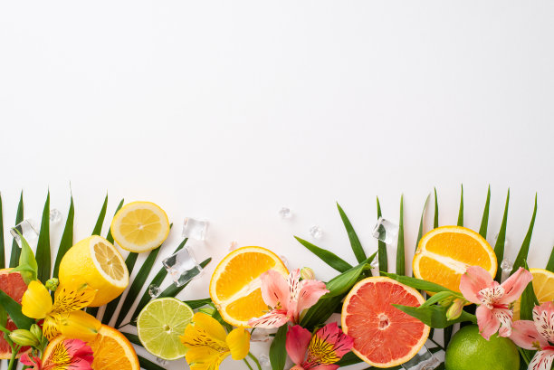 充满活力的夏季水果和花卉概念。在白色背景上的扁桃花与柑橘片和棕榈叶的俯视图，留有文字或广告的空间图片下载