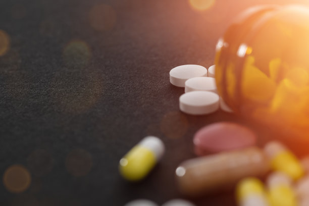 各种药丸从鲜红的橙色药瓶中溢出。图片下载