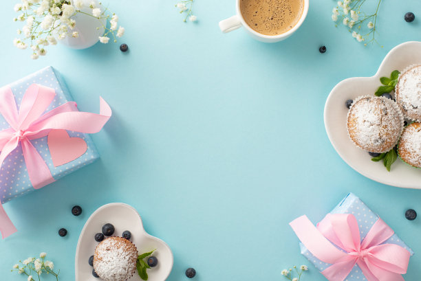母亲节早餐概念。顶视图扁平的纸杯蛋糕，礼物，咖啡，和吉思非亚花在一个柔和的蓝色背景。使用空的空间进行个性化的信息或广告图片下载