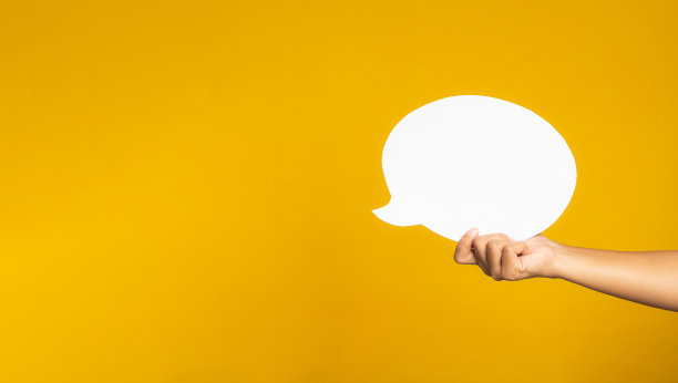 手里拿着一个黄色背景的白色演讲气球。图片下载