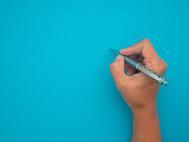 手握一支笔在蓝色背景上的女人。图片下载