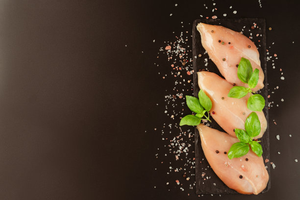 生新鲜的鸡肉片与新鲜的香草在黑色的背景。副本的空间。零售食品。有机食品，健康饮食。食品的概念。前视图。鸡胸片。关闭了。生鸡肉。图片下载