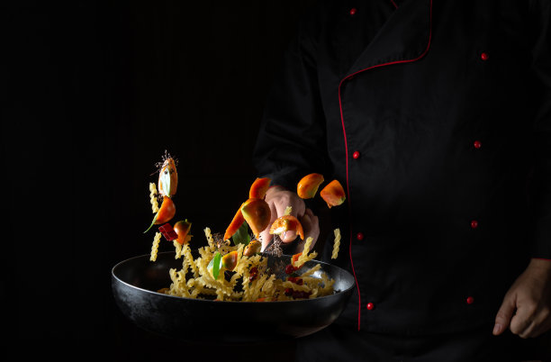 厨师在黑色背景的热锅里用蒸汽准备食物。餐厅和酒店的服务理念。加香料和蔬菜的泰式面食图片下载