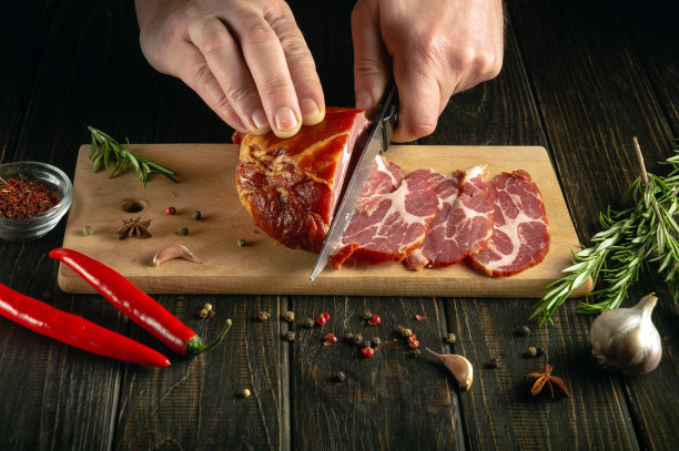 厨师用刀将熏牛肉切成薄片的特写镜头。黑色背景上的快餐概念。图片下载