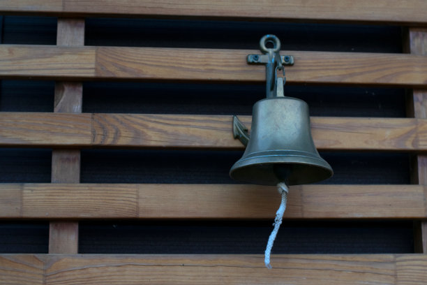 海钟与锚设计和花边挂在木墙上。欢迎晚宴或服务铃图片下载