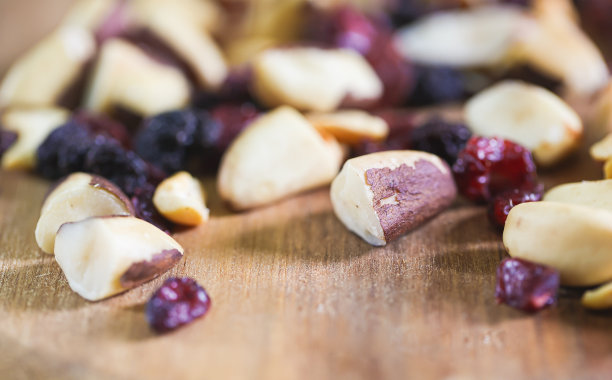 板栗、巴西坚果和葡萄干混合在一块木板上的微距照片。图片下载