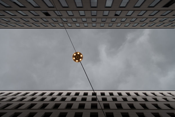 街灯在两座摩天大楼之间的底部视图和戏剧性的暴风雨天空图片下载