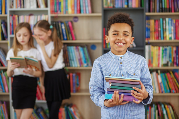 非裔美国小男孩在学校图书馆选书。每天阅读的好处。图片下载