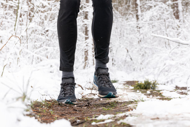 人的腿在林间小路上奔跑。这个人穿着旧跑鞋跑步。图片下载