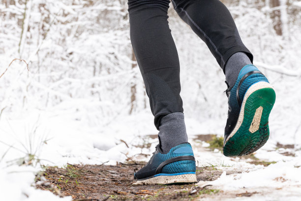 人的腿在林间小路上奔跑。这个人穿着旧跑鞋跑步。图片下载