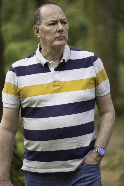 一位60岁的老人在树林里悠闲地散步图片下载