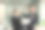 两名年轻的商人看着笔记本电脑，微笑着表示生意按照他们的计划成功了，他们的同事互相交谈，描述了良好的伙伴关系图片下载