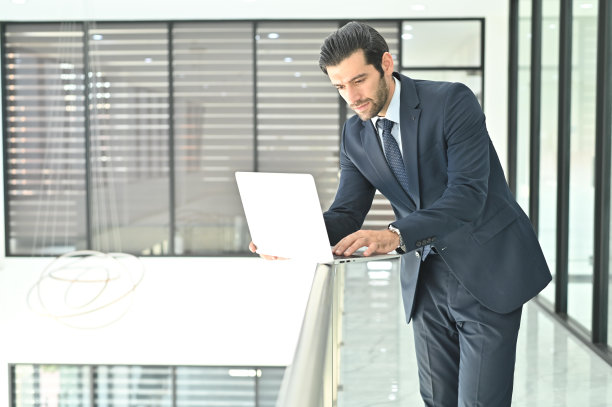 一个商人在办公室工作到很晚的时候使用笔记本电脑图片下载