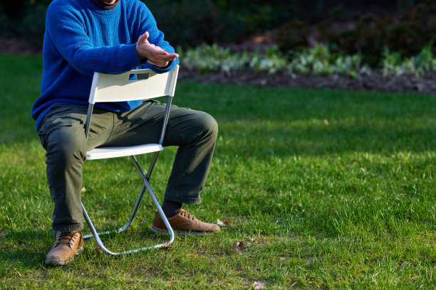 一个男人坐在草坪上的白色折叠椅上图片下载