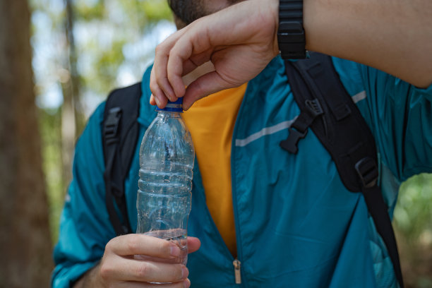 一个年轻人在森林里喝水的特写图片下载