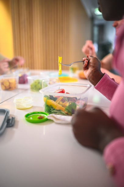 年轻的女员工用塑料容器吃沙拉图片下载