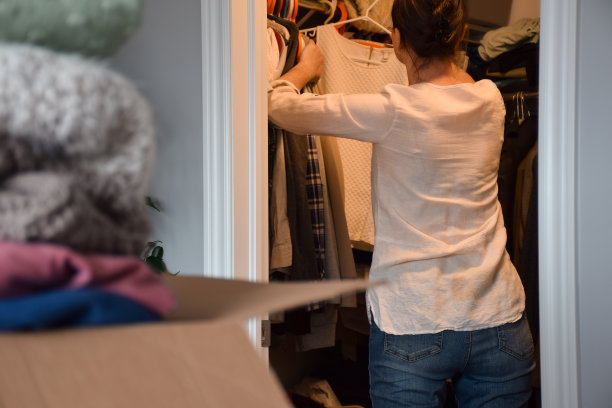 女人从后面走进去，在衣橱里整理她的衣服图片下载
