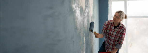 年轻的金发女郎在新房子里用油漆滚筒刷内墙，家居装饰理念。本空间图片下载