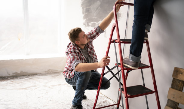 年轻的夫妇一起做公寓装修，在家里修理和粉刷墙壁。图片下载