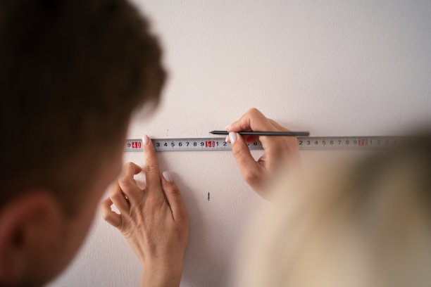 年轻夫妇用卷尺量墙，一起做公寓维修。搬迁改造后的活动。图片下载