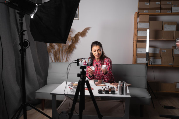 社交媒体概念上的商业在线影响者。一位女博主正在展示如何化妆和使用化妆品。在摄像机前录制视频博客视频直播在家里。图片下载