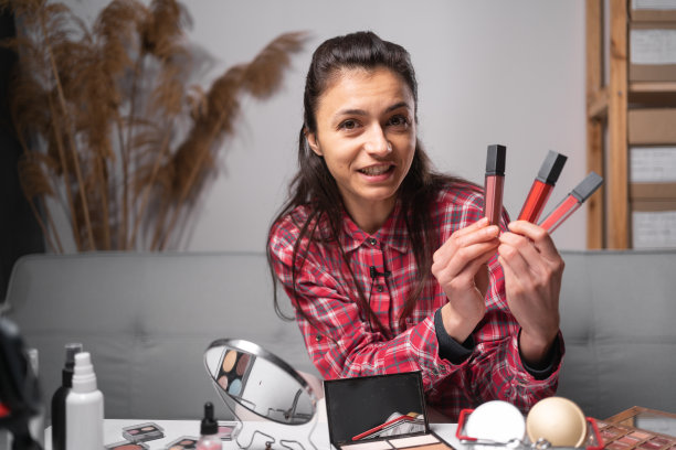 有影响力的西班牙裔女孩在家庭工作室直播化妆品评论。女视频博主比较口红。专业美妆师博主录制化妆教程图片下载