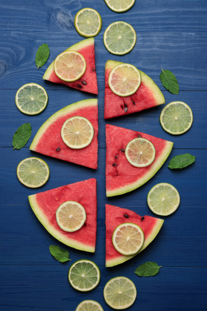 美味的西瓜片和青柠放在蓝色的木桌上，平铺着图片下载