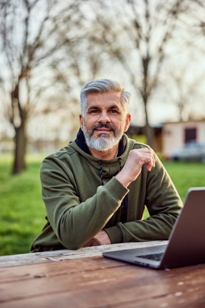 一个微笑的老年商人在笔记本电脑前工作的肖像。图片下载