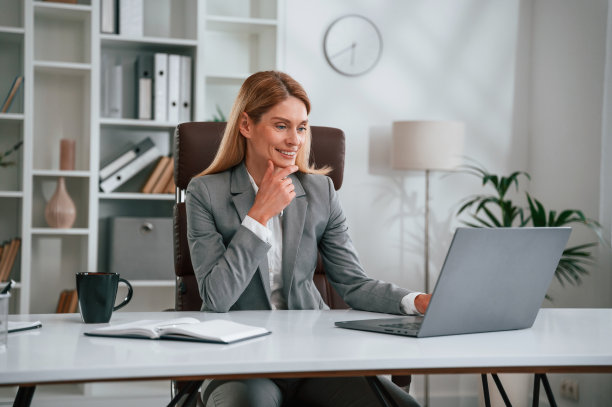 忙着用笔记本电脑。穿着正装的女士正在办公室工作图片下载