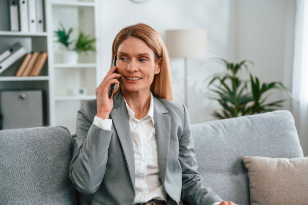 有个电话。穿正装的女人在家，坐在沙发上图片下载